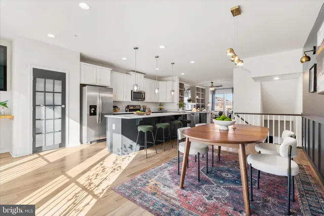 a kitchen with stainless steel appliances kitchen island granite countertop a dining table chairs and refrigerator