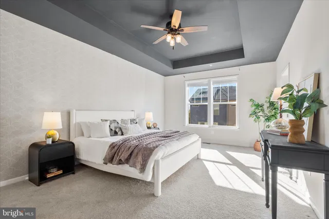 a spacious bedroom with a bed a chandelier and a large window