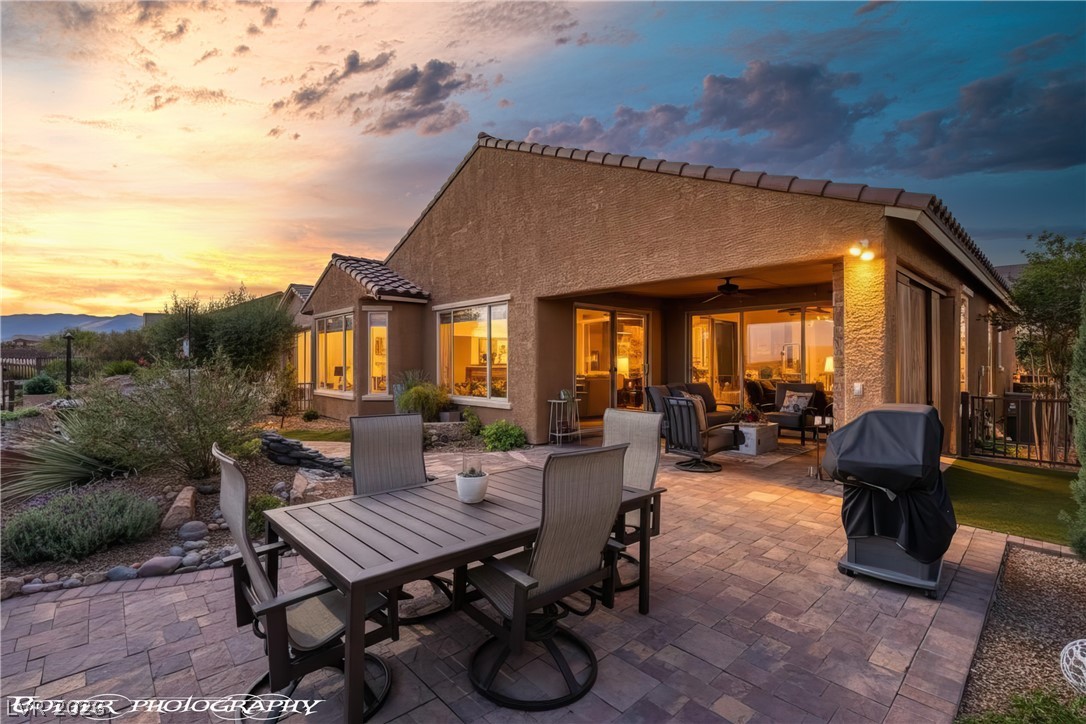 Patio terrace at dusk featuring a patio, a ceiling fan, an outdoor living / dining area, and a grill