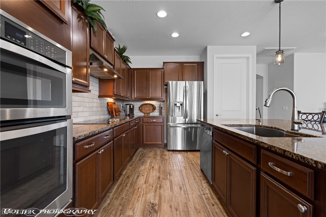 1262 Serenity Ridge Court Mesquite, NV 89034 - Photo 47 of 74 Kitchen featuring stainless steel appliances, dark stone counters, decorative backsplash, and light wood-style floors