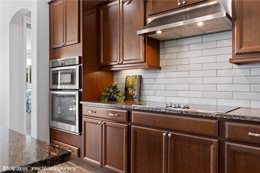 1262 Serenity Ridge Court Mesquite, NV 89034 - Photo 50 of 74 Kitchen with dark stone counters, stainless steel double oven, backsplash, black electric stovetop, and arched walkways