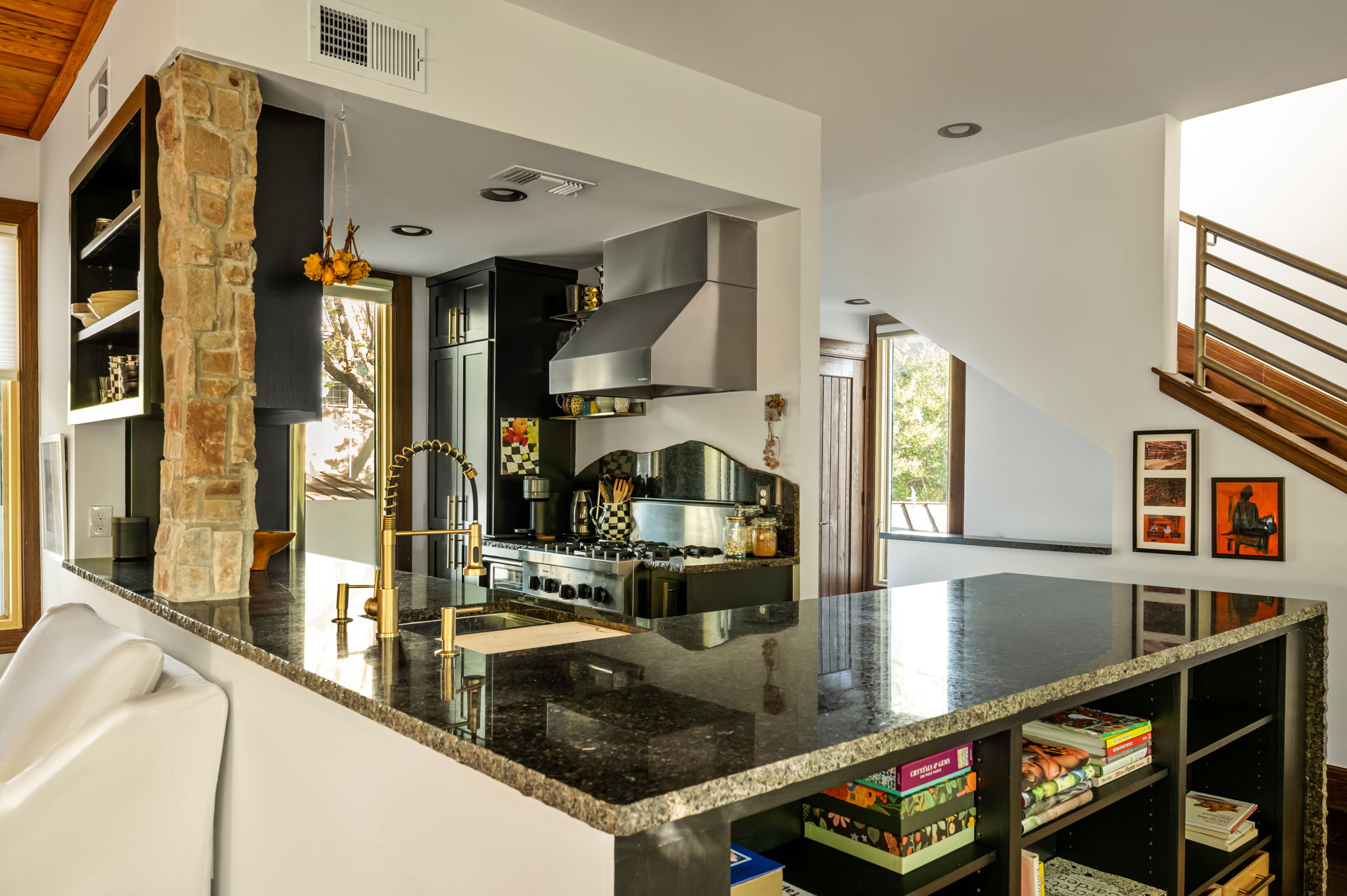 1111 West 12th Street, Unit 107 Austin, TX 78703 - Photo 21 of 38 Open-concept kitchen featuring dark cabinetry, a stainless steel range hood, and a gold-finish gooseneck faucet