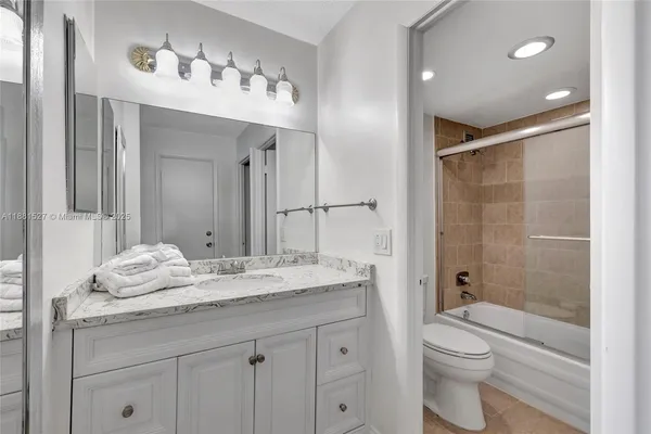 a bathroom with a granite countertop sink a toilet and a large mirror