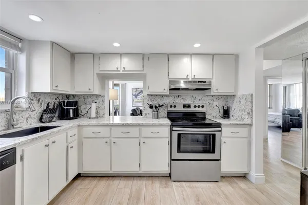 a kitchen with white cabinets stainless steel appliances and sink
