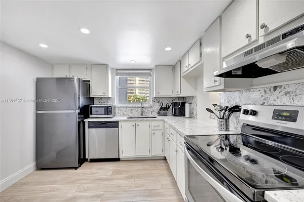 a kitchen with cabinets stainless steel appliances and wooden floor