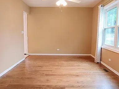 a view of an empty room with wooden floor and a window