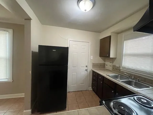 a kitchen with a sink a refrigerator and a stove top oven