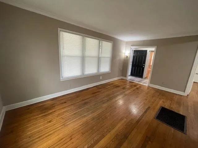 a view of an empty room with wooden floor and a window