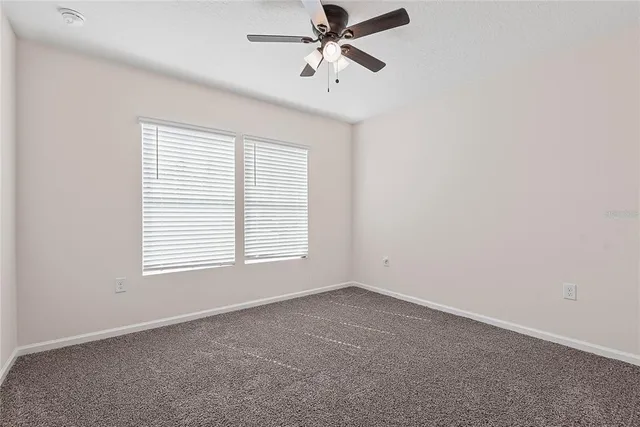 an empty room with a window and a fan