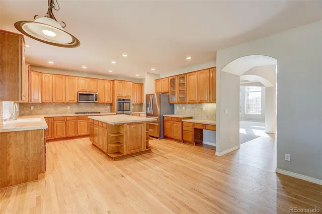 a large kitchen with stainless steel appliances granite countertop a large counter top a stove and a wooden floors