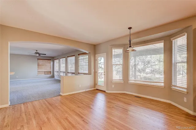 a view of an empty room with a window and wooden floor