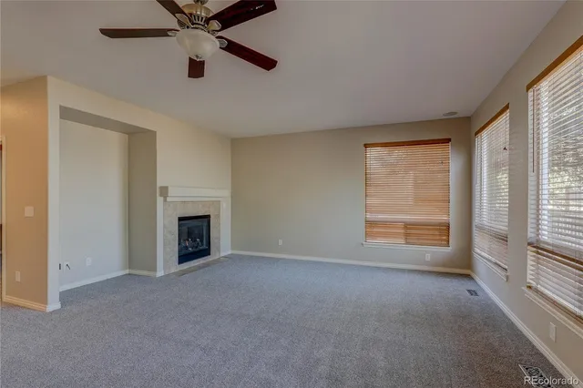 an empty room with windows and fireplace