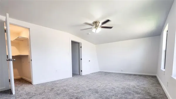 an empty room with a ceiling fan and a window