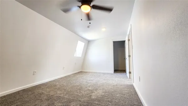 an empty room with a chandelier fan and windows