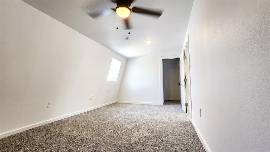 401 East Pierce Street Winters, TX 79567 - Photo 17 of 25 an empty room with a chandelier fan and windows