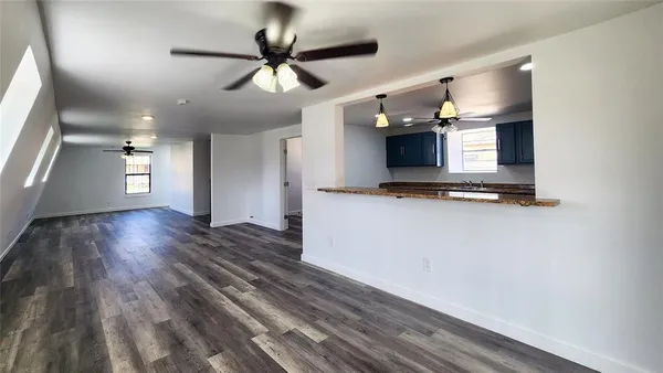 a view of kitchen and empty room with wooden floor