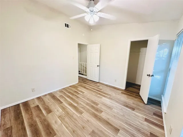 an empty room with wooden floor and fan