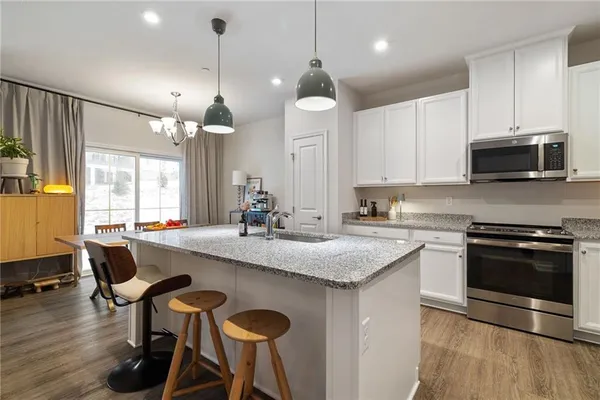 a kitchen with granite countertop a sink a counter space appliances and cabinets