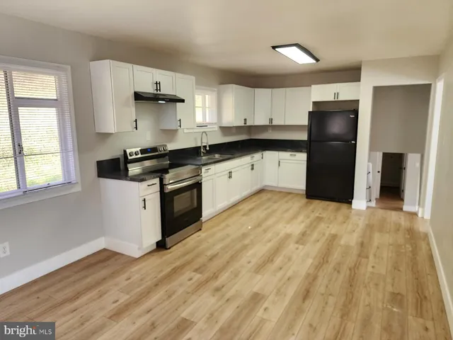 a kitchen with granite countertop a refrigerator stove top oven and sink