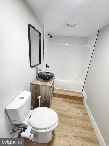 a white toilet sitting next to a bathroom sink and a mirror