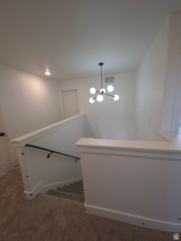 1267 West 2350 South Perry, UT 84302 - Photo 9 of 20 White staircase featuring a modern Sputnik-style chandelier, contrasting black handrail, and plush carpeted steps