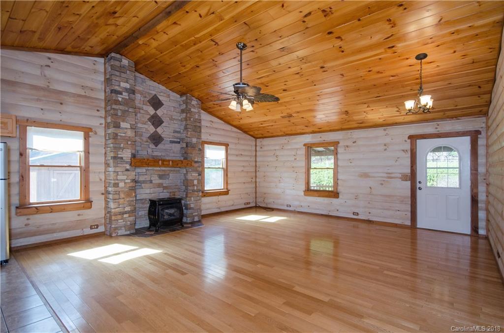139 Stanley Ln Mill Spring, Unit 8 Mill Spring, NC 28756 - Photo 3 of 22 an empty room with wooden floor fireplace and windows