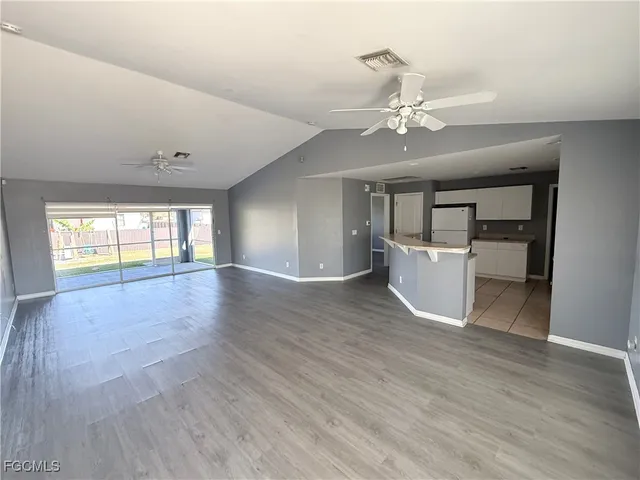 a view of an empty room with window and wooden floor