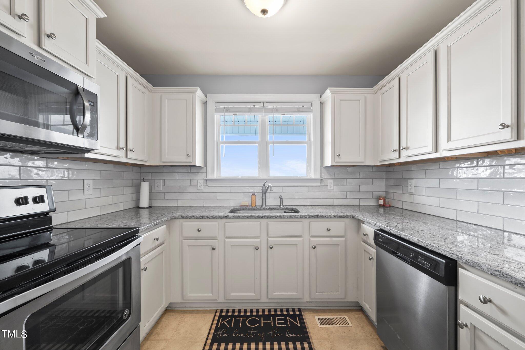 3195 Johnston County Road Angier, NC 27501 - Photo 12 of 31 a kitchen with stainless steel appliances granite countertop a sink stove oven and white cabinets