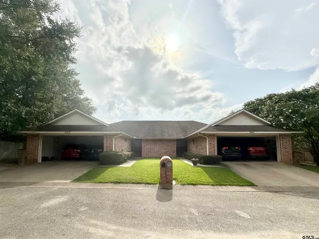 a front view of a house with a garden and trees