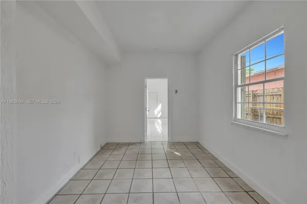 a view of an empty room with window and bathroom