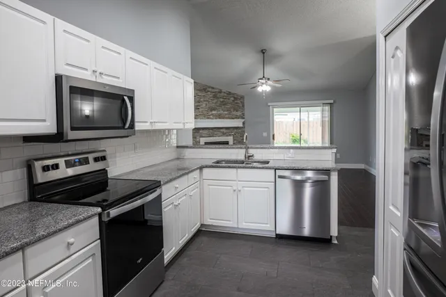 a kitchen with stainless steel appliances granite countertop a stove a sink and a microwave