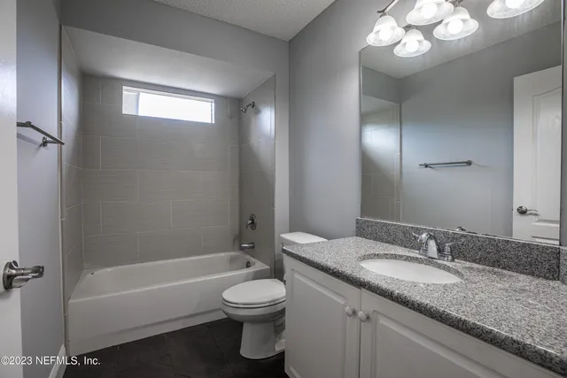a bathroom with a granite countertop sink a toilet and bathtub