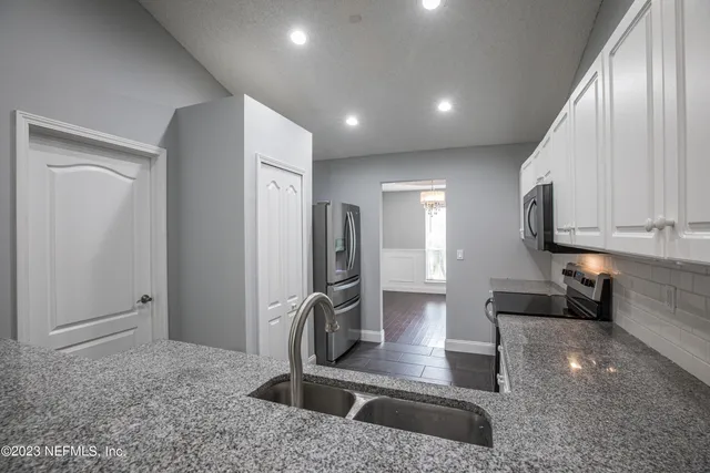 a kitchen with stainless steel appliances granite countertop a sink a stove and a refrigerator