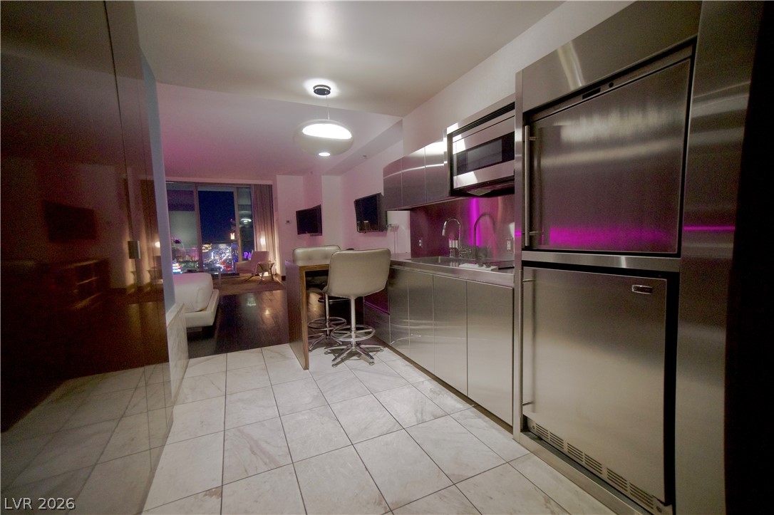 4381 West Flamingo Road, Unit 3616 Las Vegas, NV 89103 - Photo 9 of 29 A compact kitchen boasts stainless steel appliances, seamlessly flowing into a bedroom with a captivating city lights view.