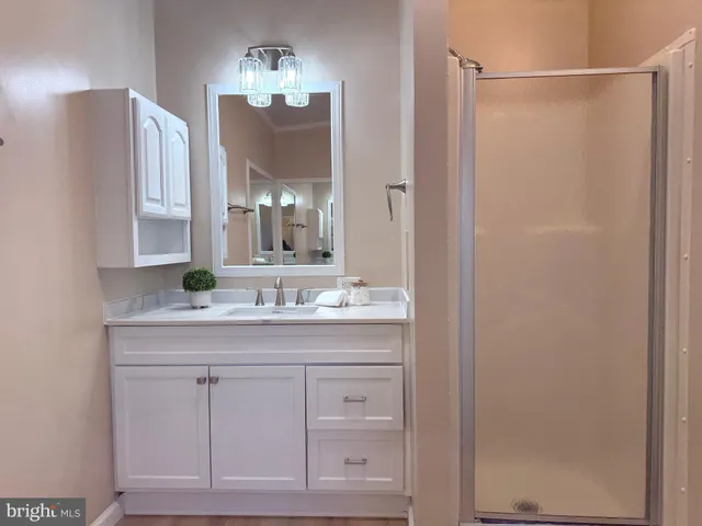 a bathroom with a granite countertop sink a mirror and a shower