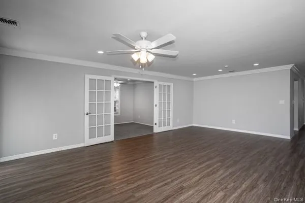 a view of an empty room with wooden floor and a ceiling fan