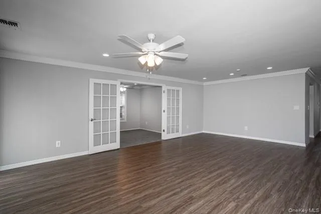 a view of an empty room with wooden floor and a ceiling fan