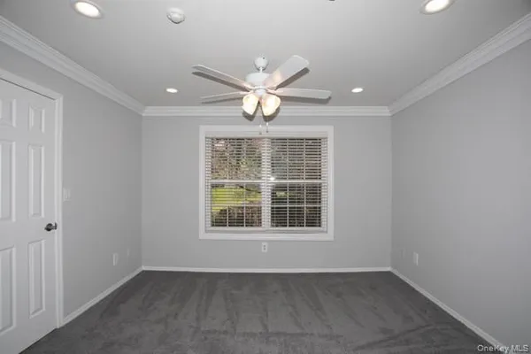 an empty room with chandelier fan and windows
