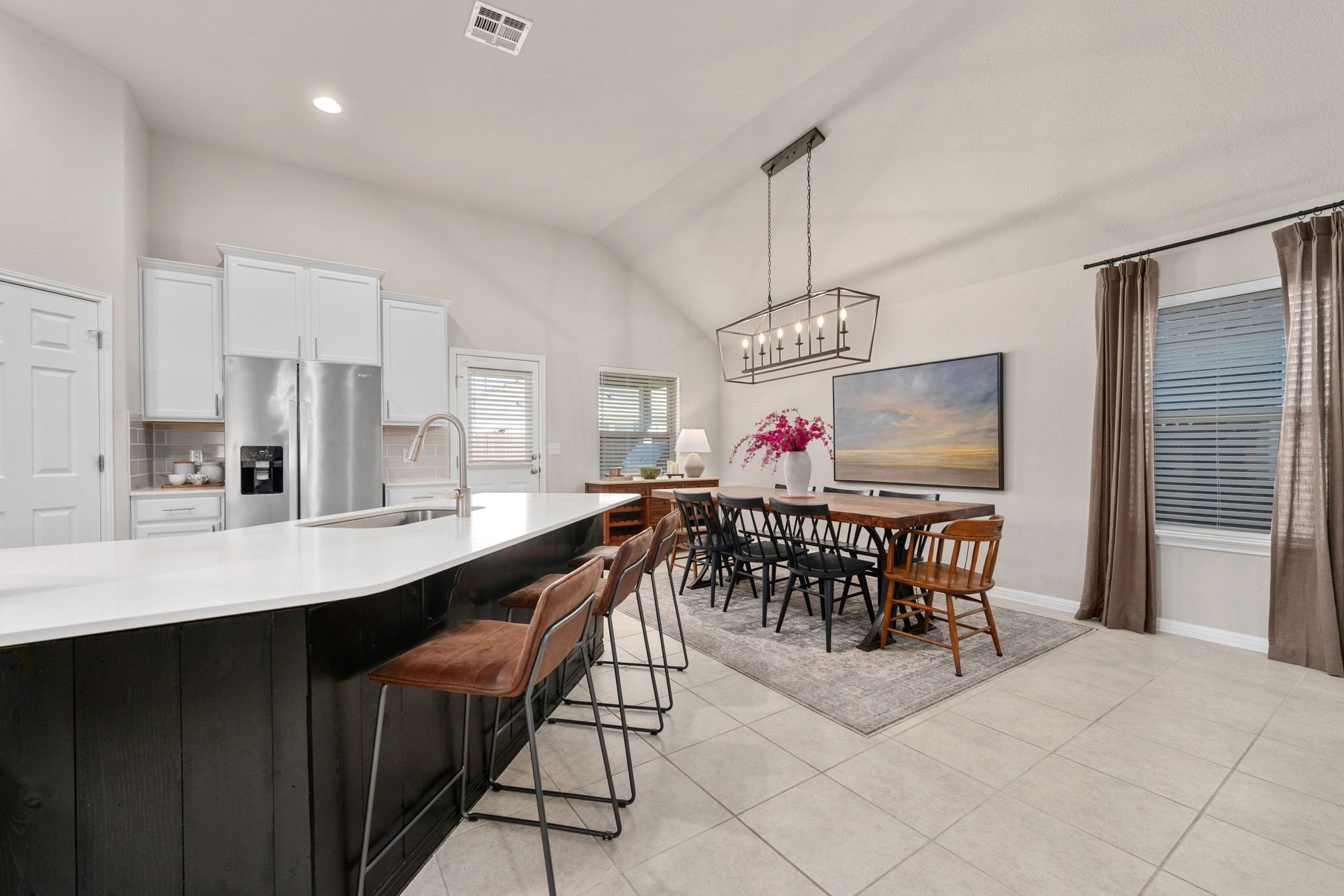 109 Findley Avenue Leander, TX 78641 - Photo 8 of 38 Vaulted ceilings continue into the dining space, open to a kitchen with tasteful backsplash, a two tone color scheme, and extended breakfast bar.