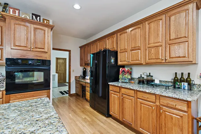 a kitchen with granite countertop wooden cabinets and a refrigerator