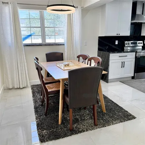 a kitchen with stainless steel appliances a refrigerator a stove a sink dishwasher with a dining table and chairs