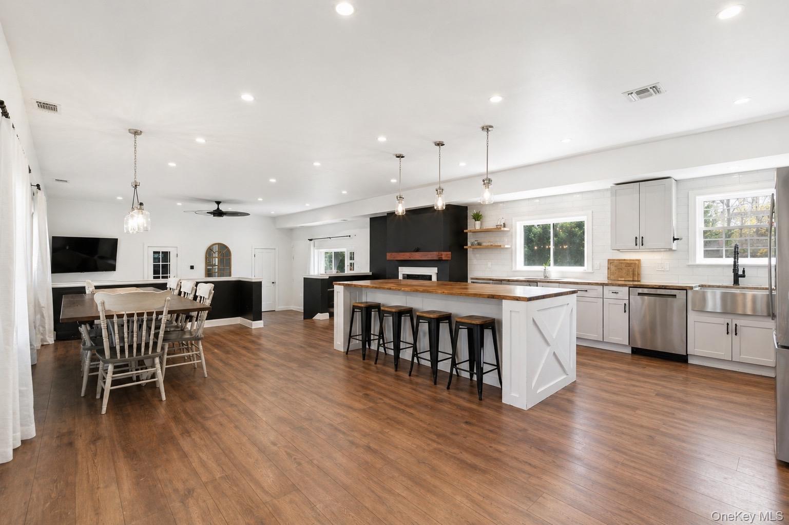 18 Pond Road Holbrook, NY 11741 - Photo 2 of 41 Spacious open-concept kitchen and dining area featuring wood-finish flooring, white shaker cabinetry, stainless steel appliances, and a large center island with seating