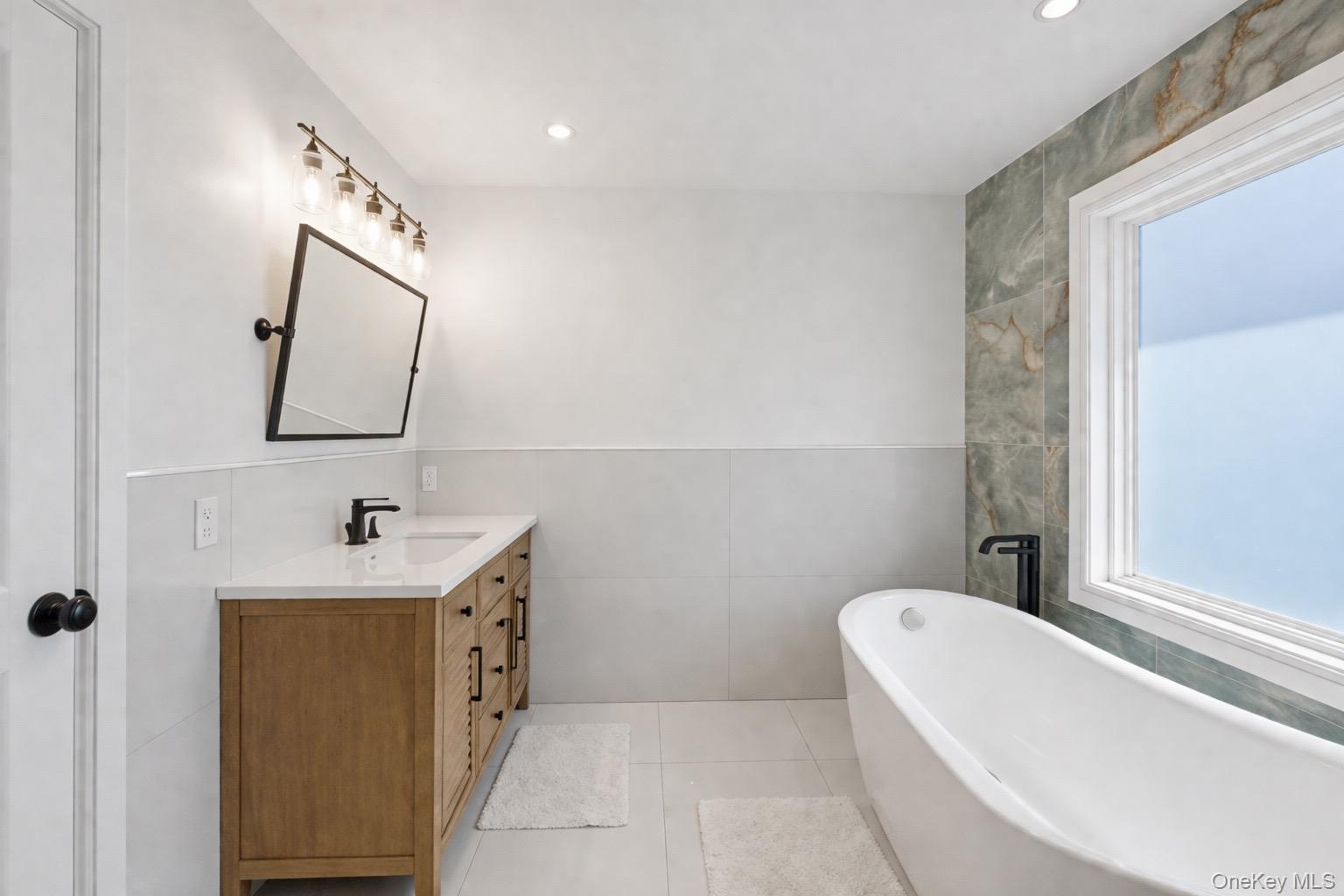 18 Pond Road Holbrook, NY 11741 - Photo 22 of 41 Primary Bathroom featuring a freestanding soaking tub, large window, wood-finish vanity with countertop, and modern black fixtures