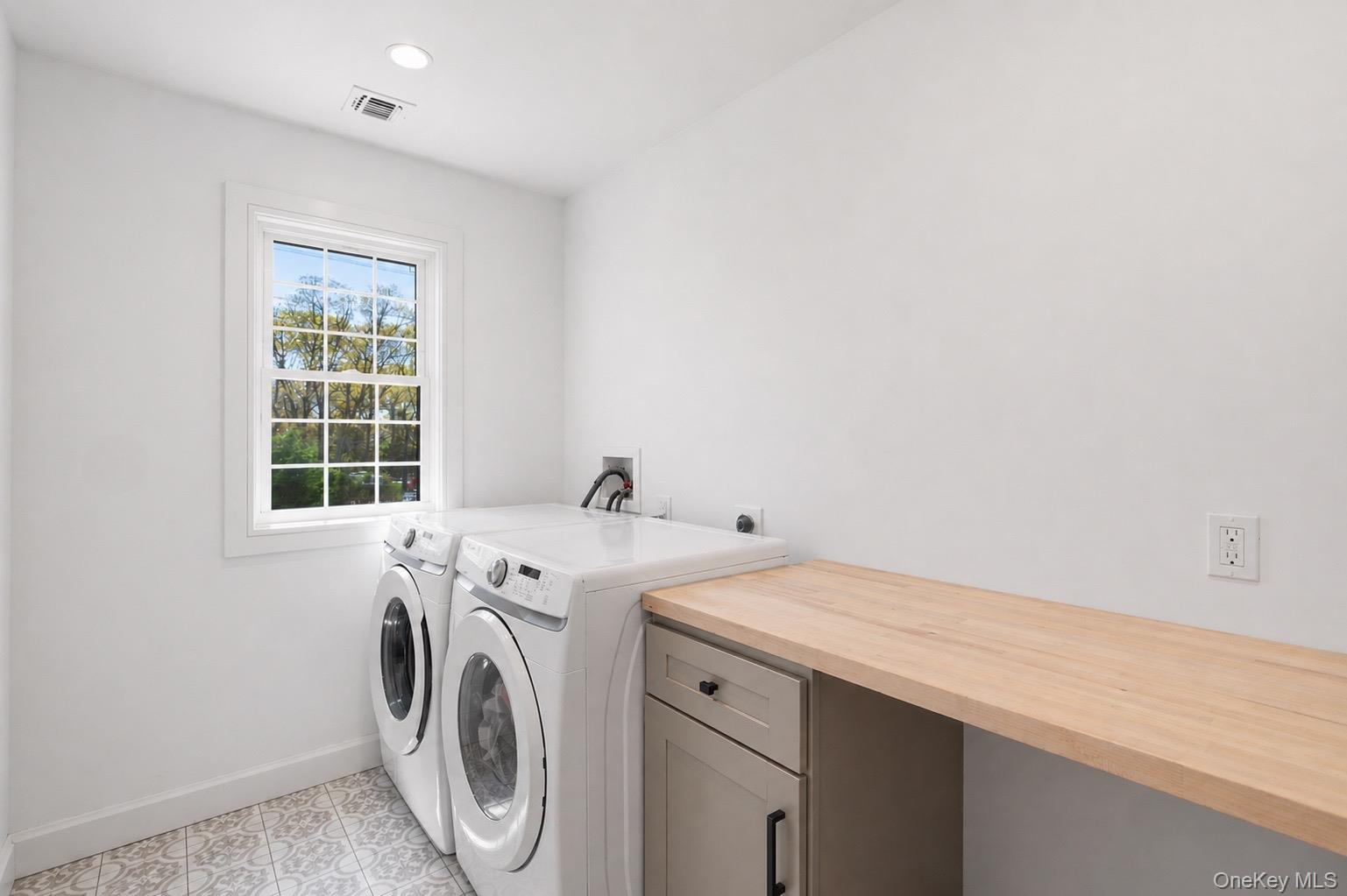 18 Pond Road Holbrook, NY 11741 - Photo 31 of 41 Laundry room featuring a single window, patterned floor tile, a light wood-finish countertop, and built-in cabinetry