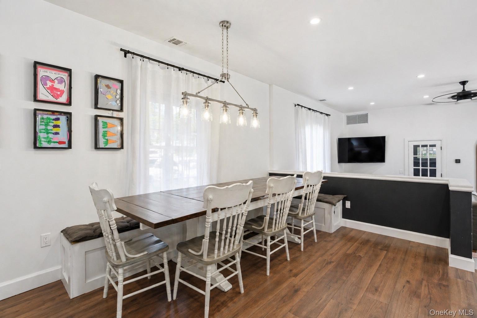 18 Pond Road Holbrook, NY 11741 - Photo 7 of 41 Dining area featuring wood-finish flooring, a linear chandelier with clear glass shades, recessed lighting, and a built-in bench