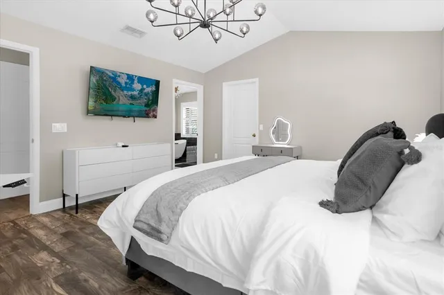 a bedroom with a bed and a flat tv screen on dresser