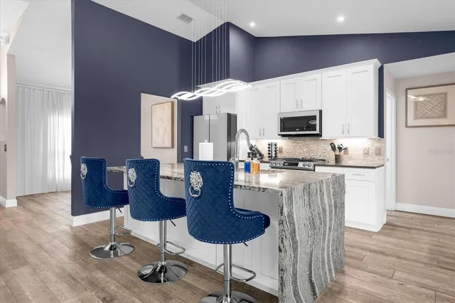 a kitchen with stainless steel appliances kitchen island granite countertop a stove a sink a microwave a dining table and chairs