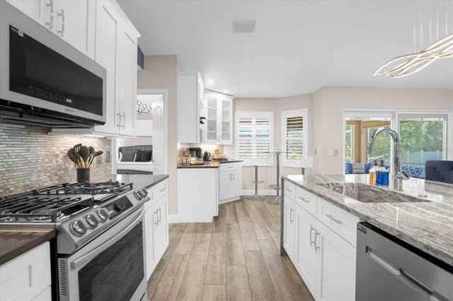 a kitchen with stainless steel appliances kitchen island granite countertop a stove a sink and a microwave