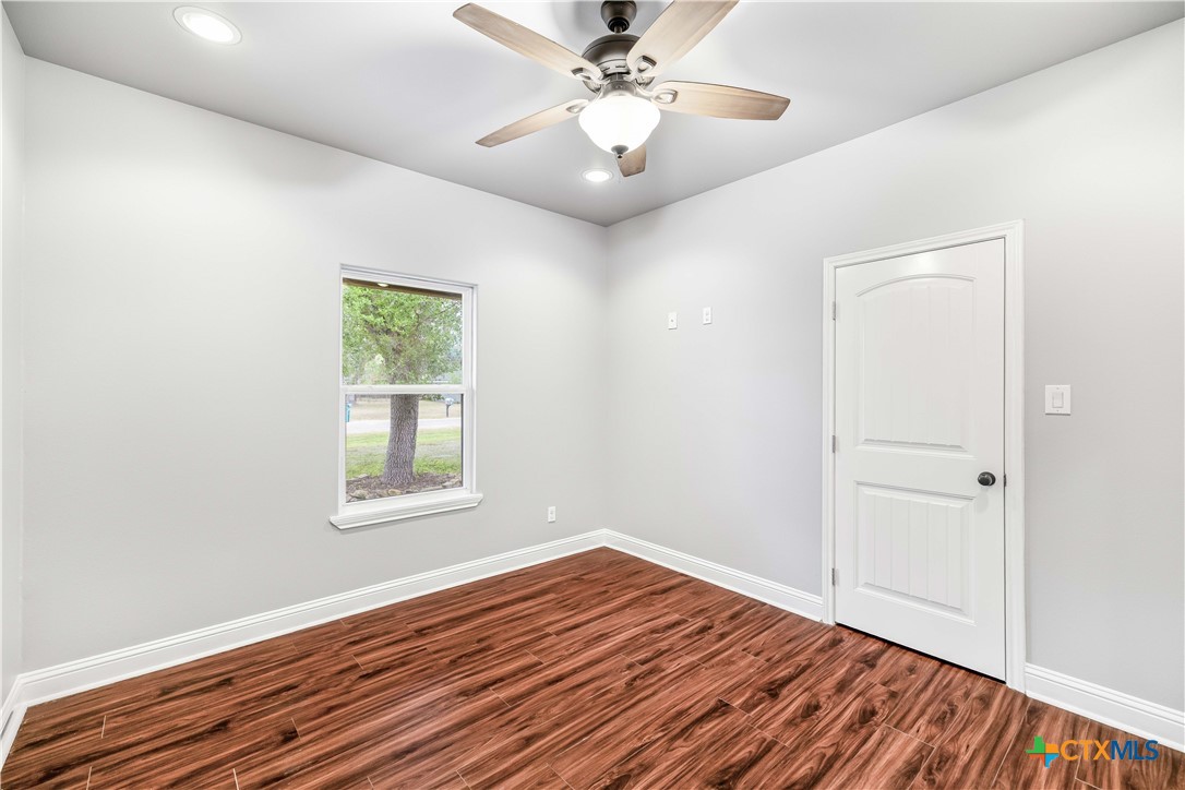 204 James Street Inez, TX 77968 - Photo 22 of 35 an empty room with wooden floor chandelier fan and windows