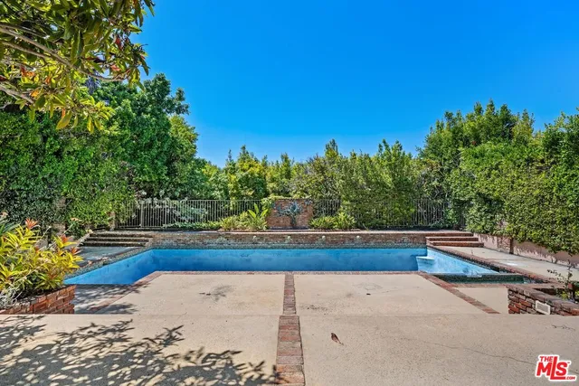 a view of backyard with swimming pool and trees in the background